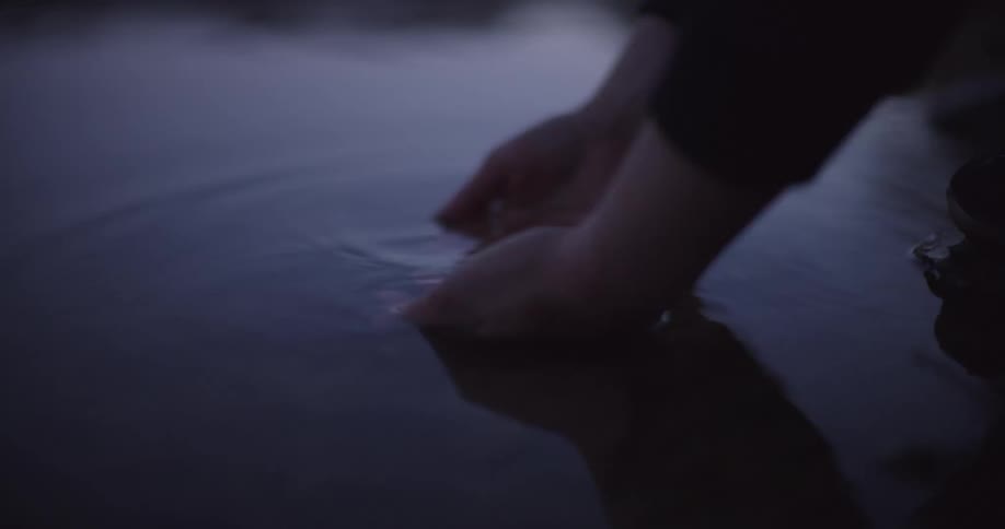Hands lowering into a puddle of water and scooping it out