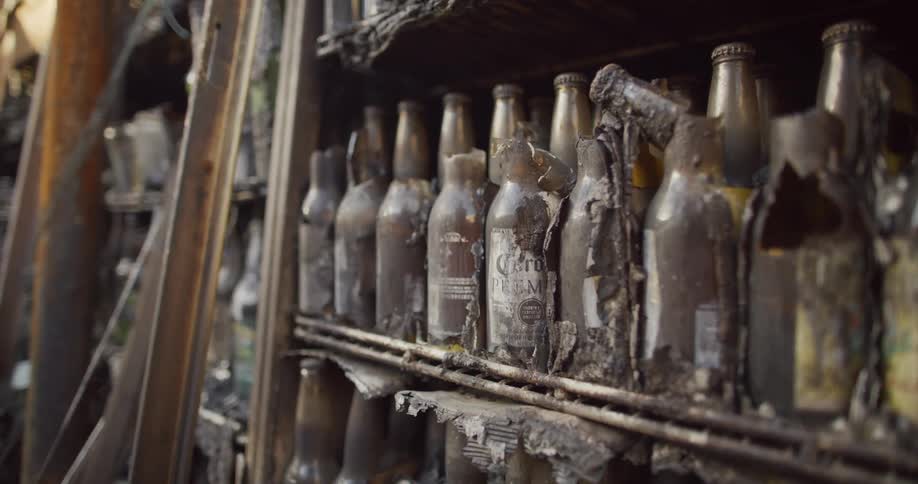 Shelves of old bottles that are broken in an abandoned space with dust and dirt