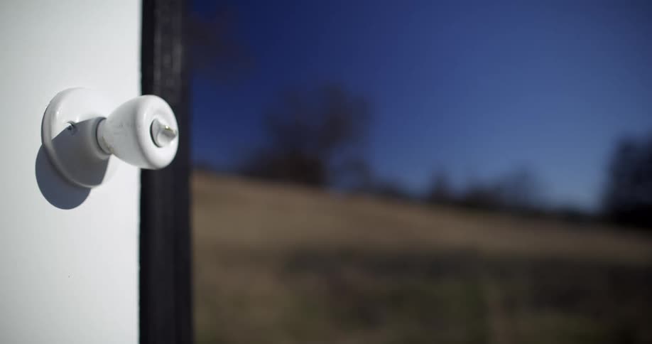 A white door unattached to any building sits in a field in the countryside