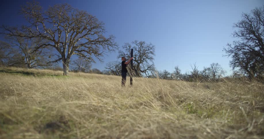 A man tries to shake down and remove a door that leads to nowhere in a field