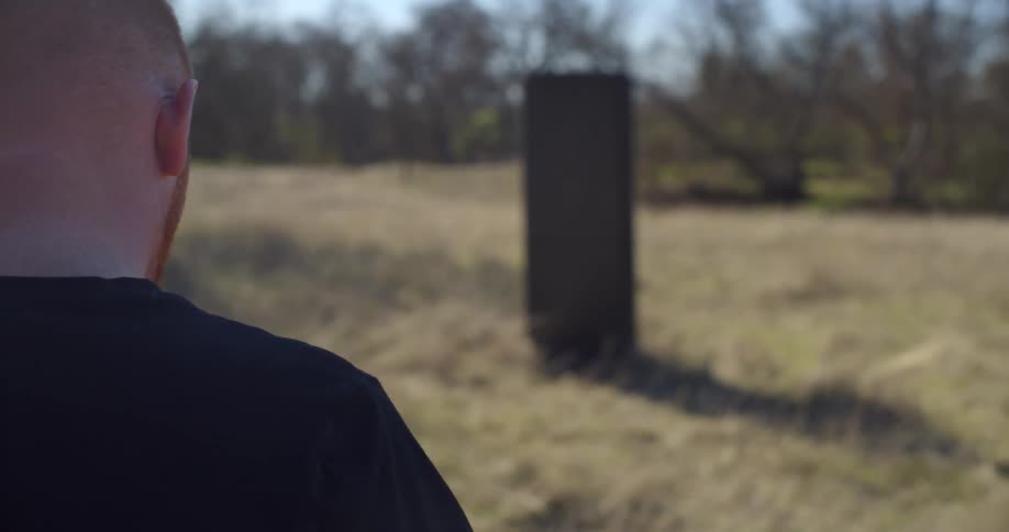 A man walks toward a structure in a field