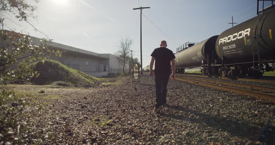 A man walks next to a train as it drives down the railway tracks