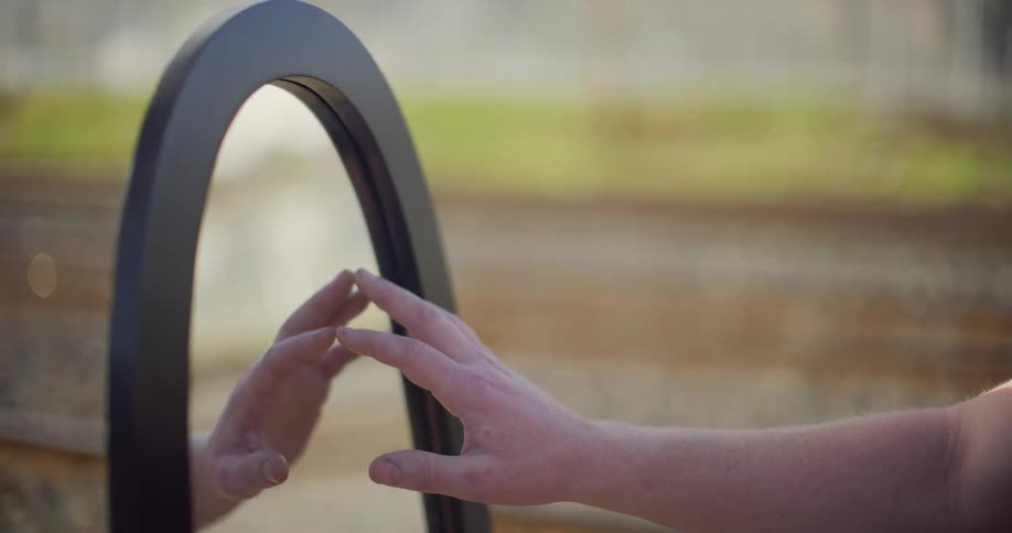 Womans hand touches the mirror outdoors