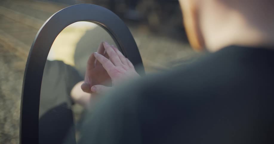 A man grazes a mirror with his fingers