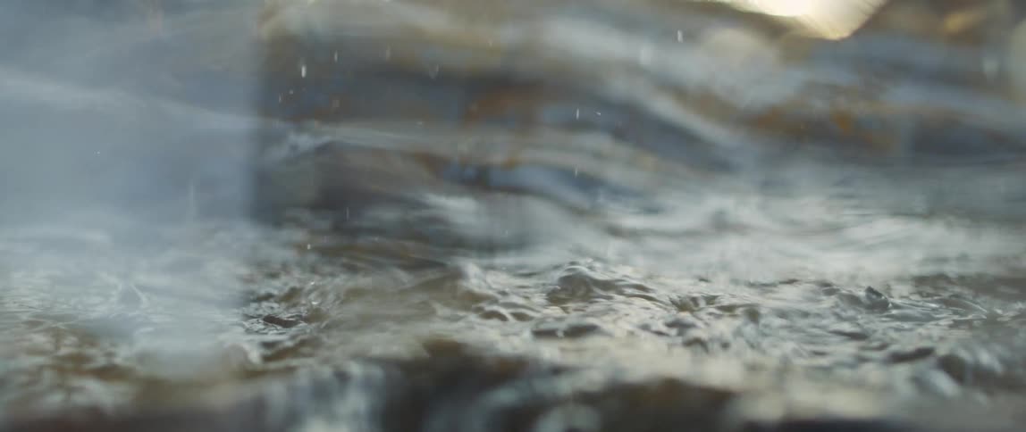 A hammer smashes an object in water and water sprays about