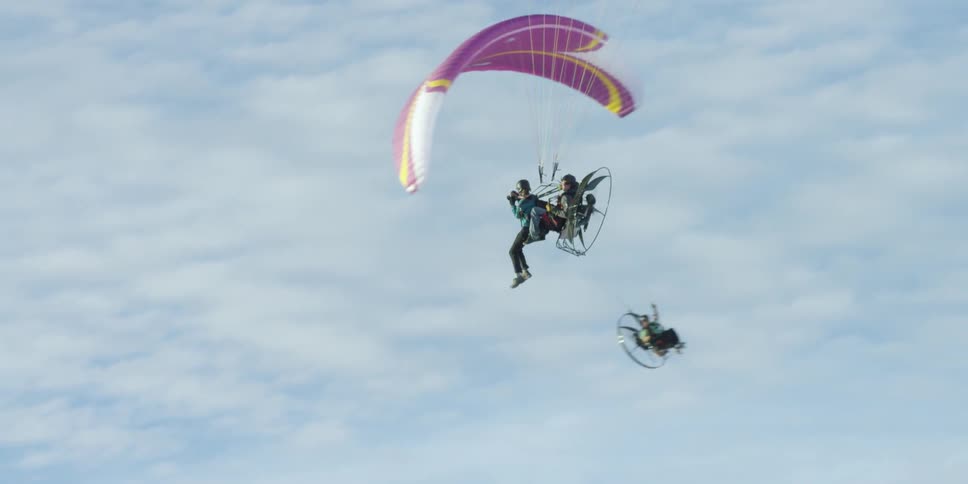 People are flying parasailing in a cloudy sky