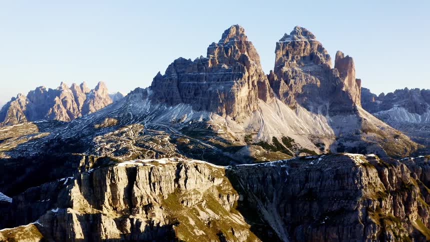 Mountain peaks with a cliff covered in light amounts of snow in day time