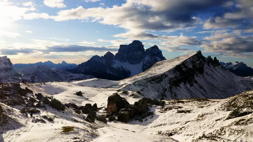 An aerial view of a mountain range with snow and blue sky