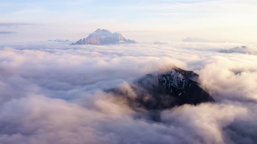 Snow covered peaks of mountains peek through heavy cloud layer