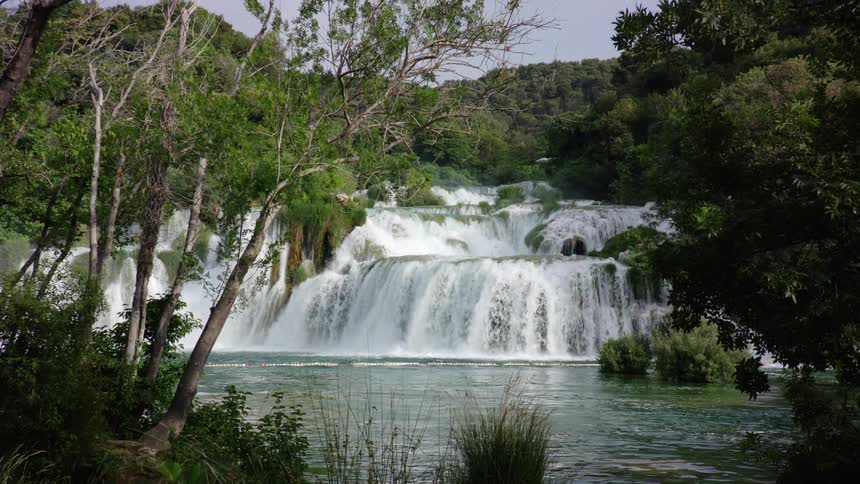 Forest waterfall flows into river on a clear day