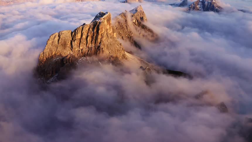 An aerial view of mountain range with a thick cloud covering in sunlight