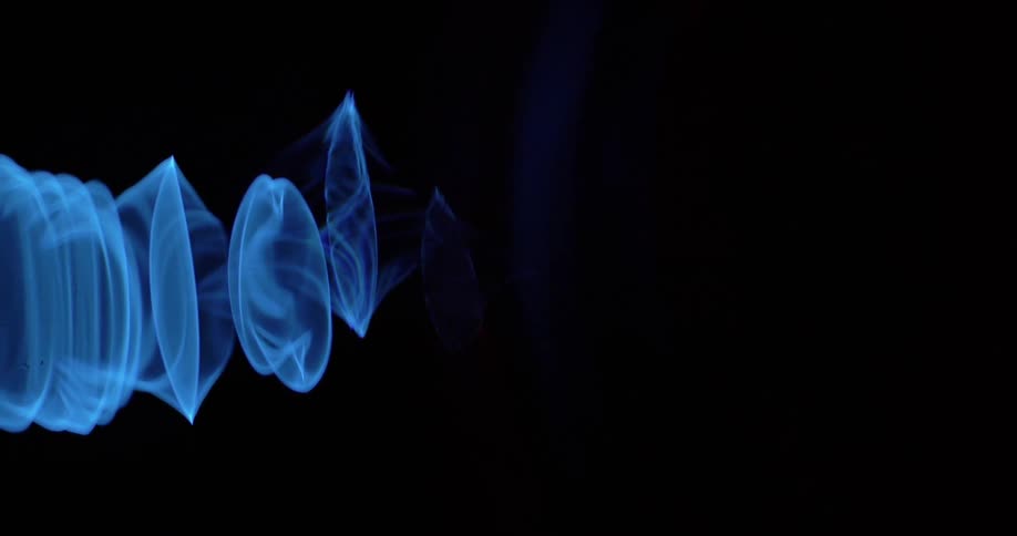 Blue smoke circle rings floating in darkness
