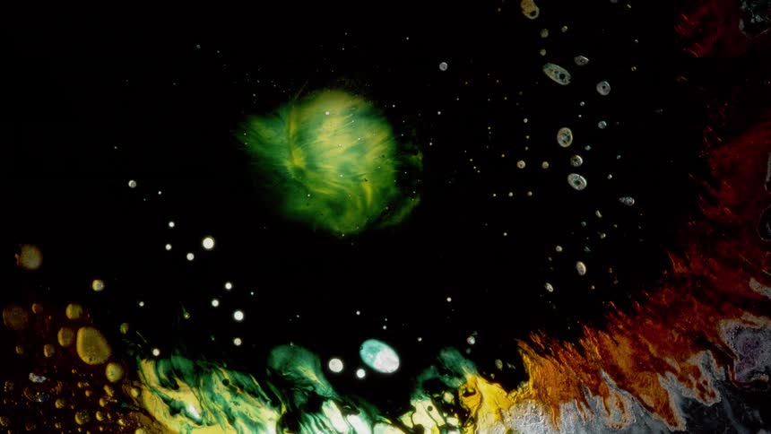Green and yellow colors explode on a black screen surrounded by a ring of different colors