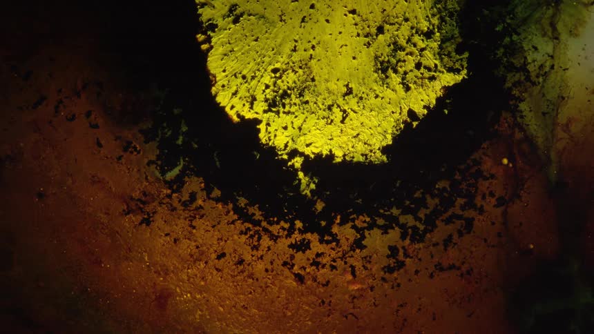 Yellow and black powders mixing into a liquid