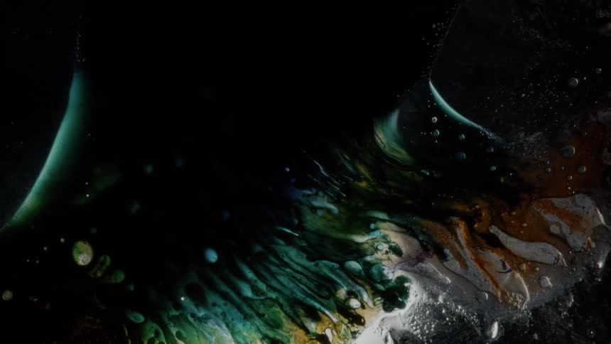 Streaks of various colors flows across surface surrounded by darkness