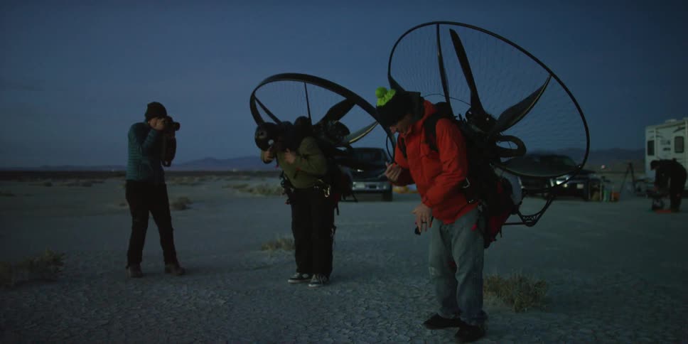 A man photographing men preparing to fly with paramotors