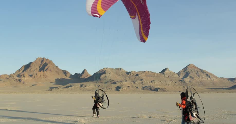 Man wearing parasail and paramotor running and flying off