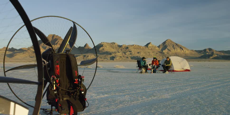 People sitting on a desolate plain next to their tent