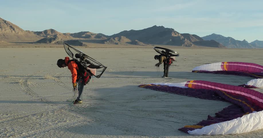 Two people preparing to go parasailing on a deserted beach