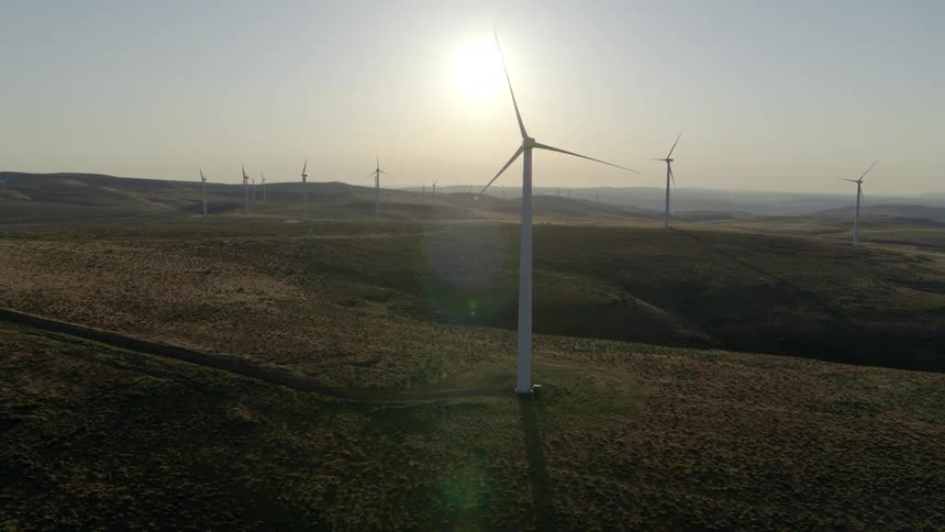Wind turbines sit perfectly still on a calm day at a large wind farm