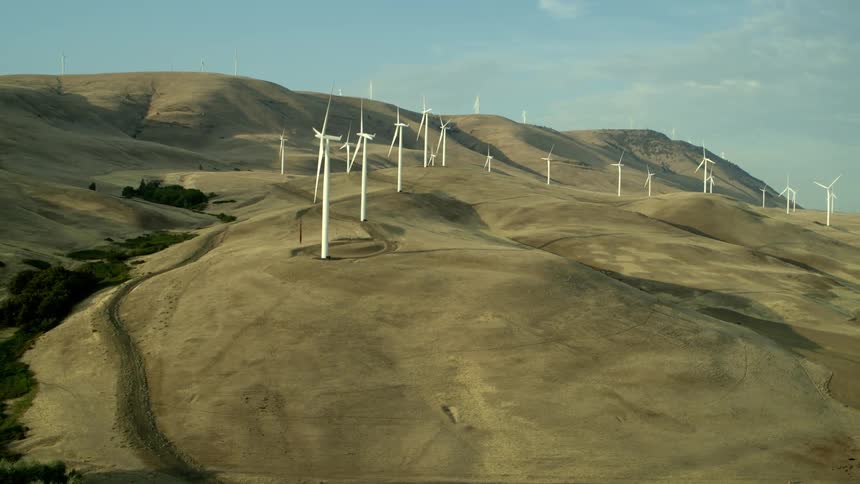 A cluster of wind turbines generating power along rugged rolling countryside