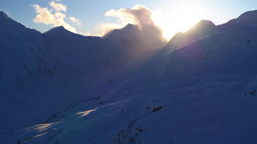 Snow covered mountains with sun shining bright above the peaks