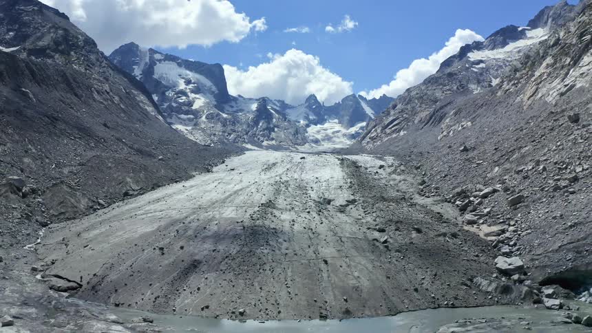 A flat icy section of land between ridges in a mountain during the day