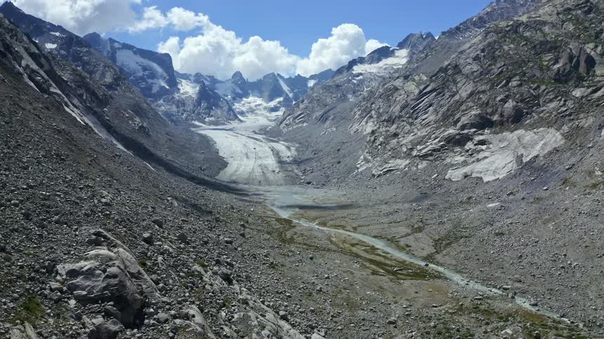 A valley is situated between a range of very rocky mountains