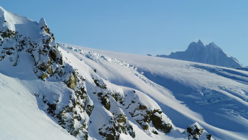 Snowy mountain slopes at day time with small rock formations