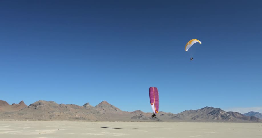 Two people are flying through the sky on paraglides