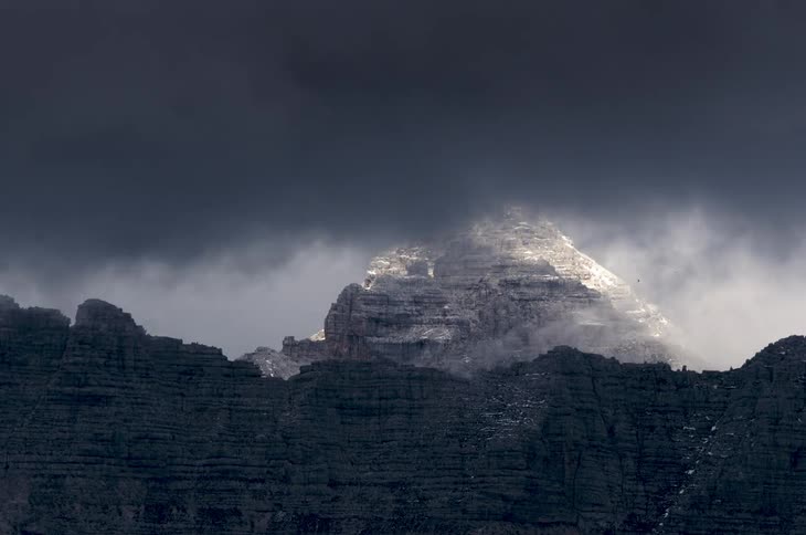 Clouds billow and pass over a rocky ridge