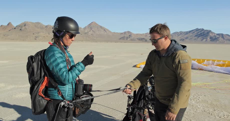 Man tightens buckles on a woman's harness