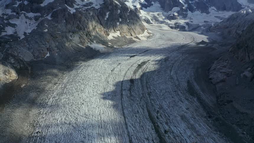An icy road with a reveal up to a mountain range in the daylight