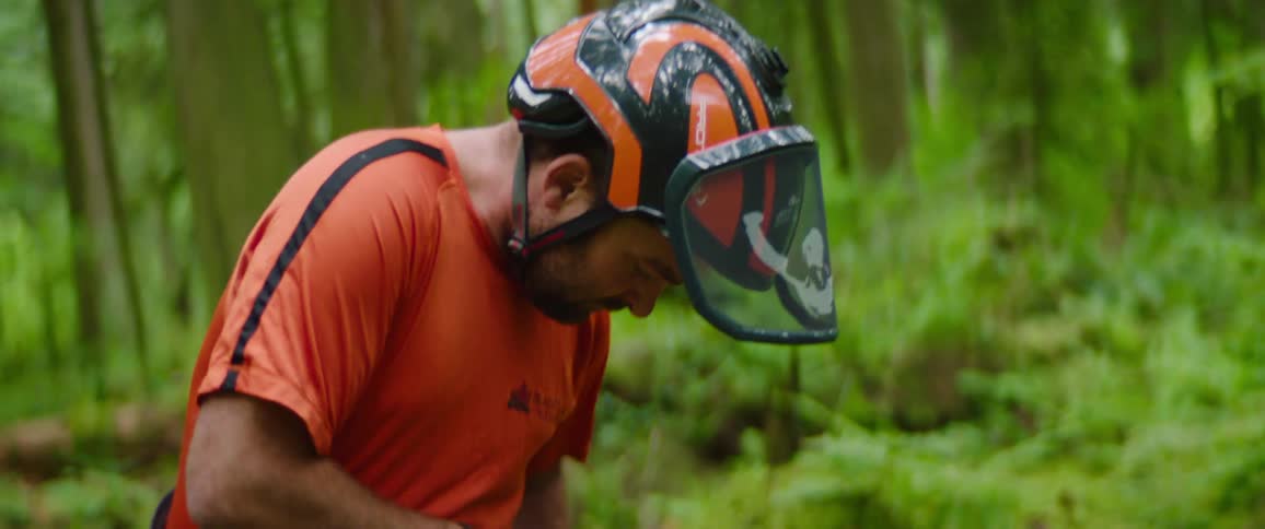 Man standing outdoors in a forest at day time securing climbing equipment