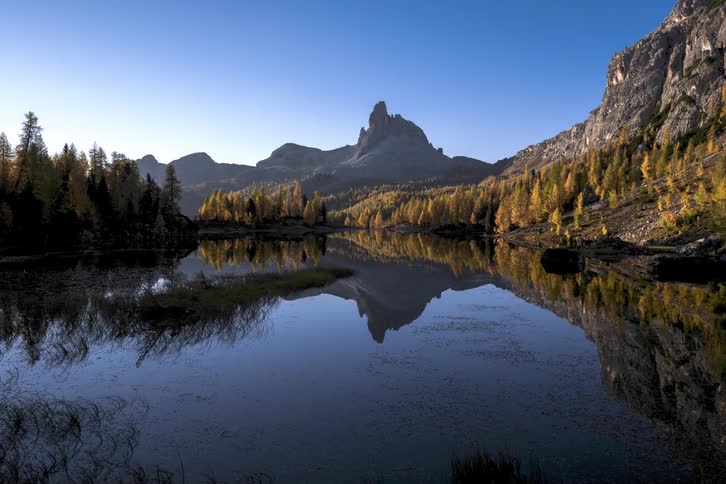 Time lapse of a lake with mountains and people walking to the shoreline