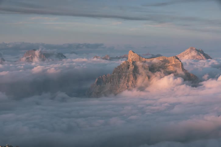 Mountain peaks high above the clouds as clouds move by