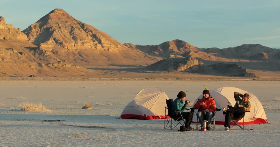 People sitting in front of tents near desert mountains