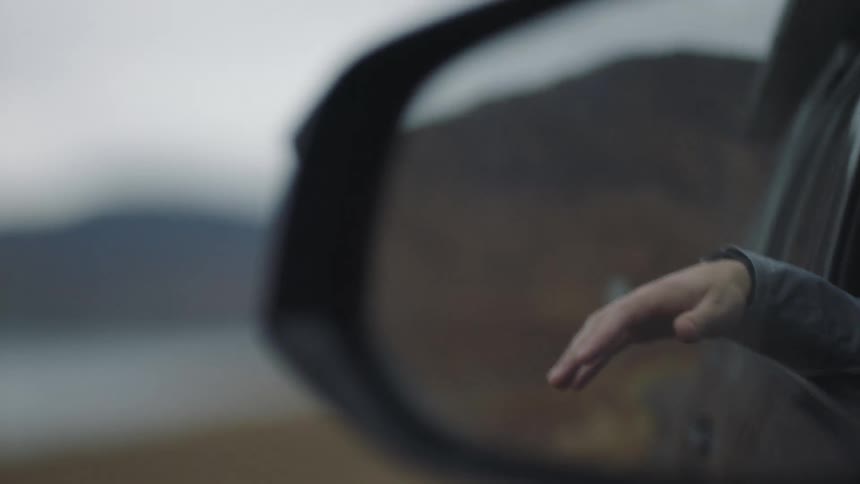 A hand is hanging out of a moving car