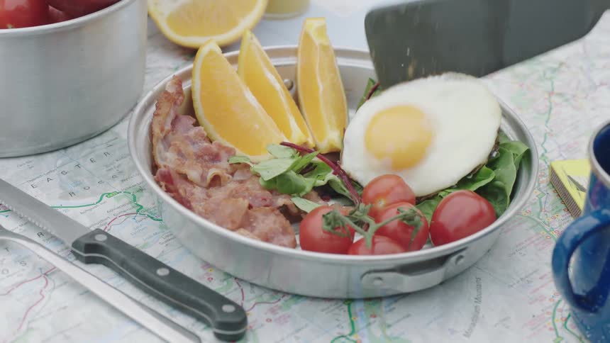 A plate of food is on a table with an egg placed on top with a spatula
