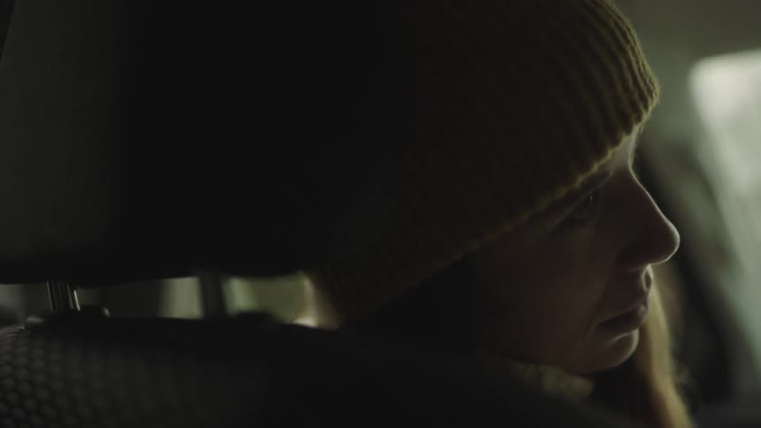 Woman sitting in a moving car sleeping with her head on the headrest at daytime
