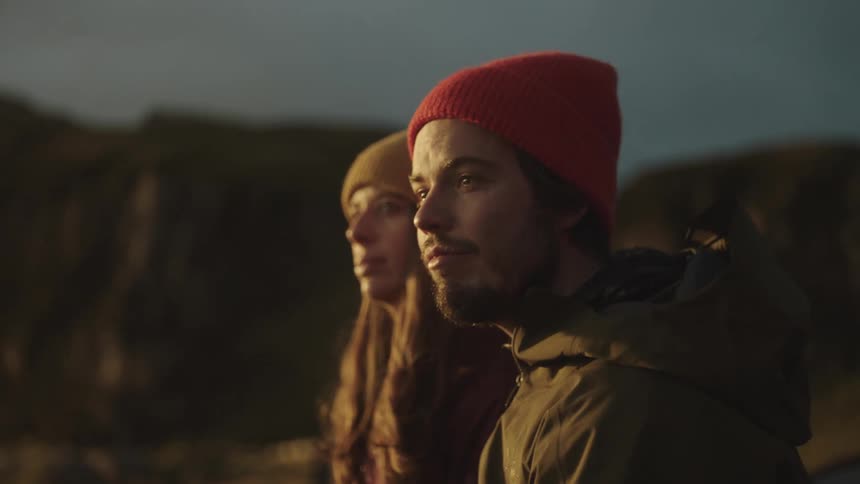 A man and a woman are next to each other and he points off in the distance