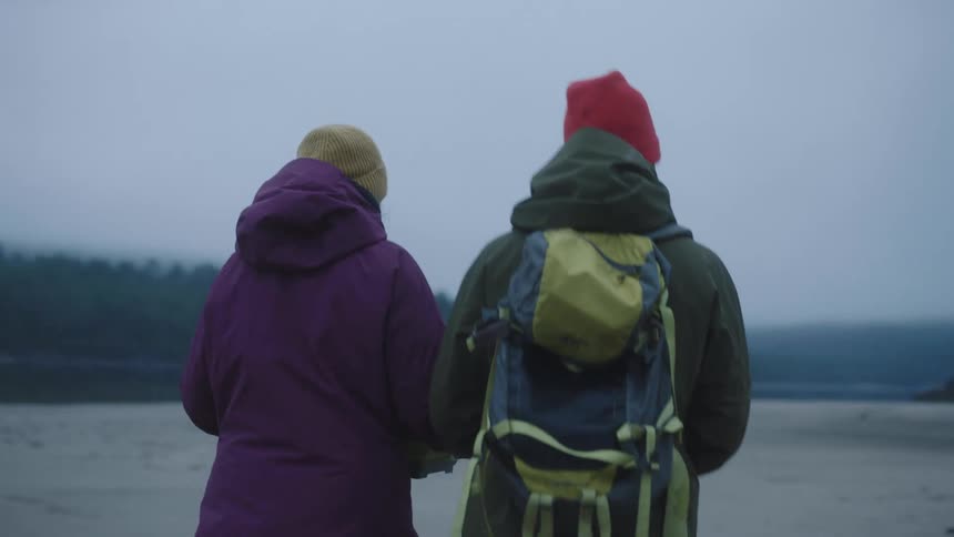 Man and a woman walking outside at day time wearing warm weather clothing and hiking backpack