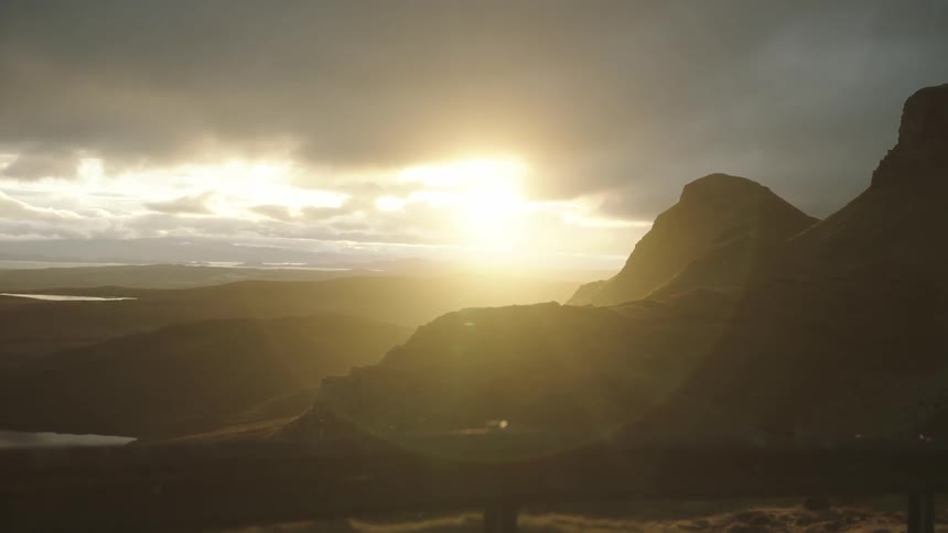 The sun goes down behind the mountains and clouds on the horizon