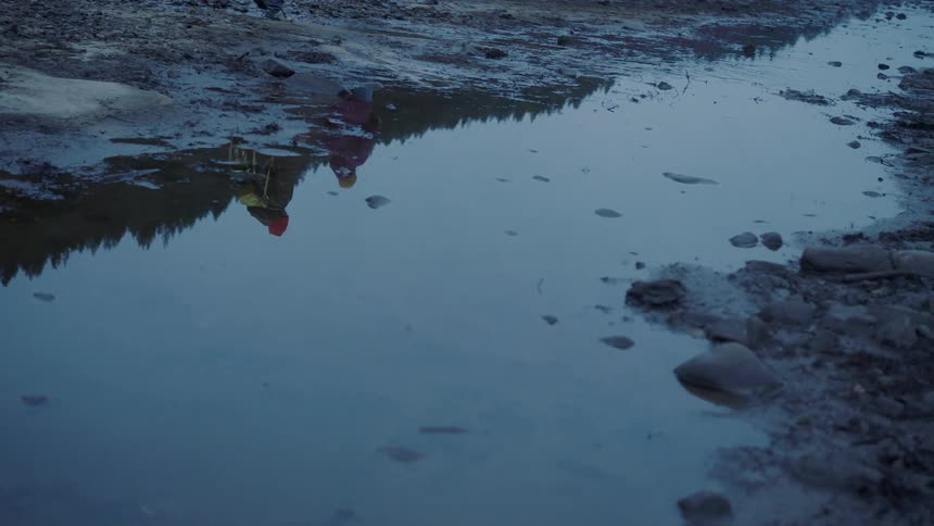 Two people hiking walking near a stream with the reflection in the water