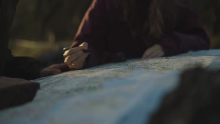 A woman writes on a map while standing outdoors with a man