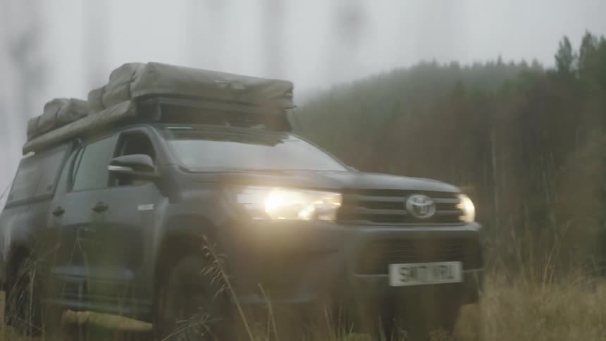 A toyota truck drives off road through a field