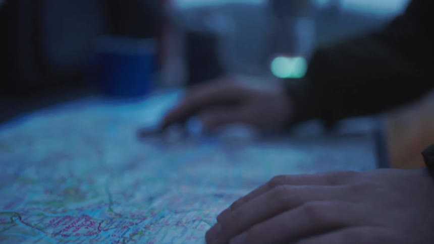 A person uses the top of a pen to trace a road on a paper map