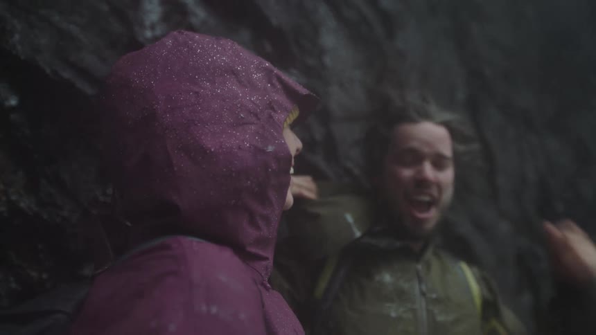 Man shaking off his hair from water standing next to a woman laughing under a downpour of water