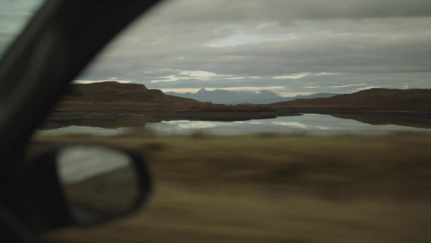 View of a lake on a cloudy day seen from a car driving on the road