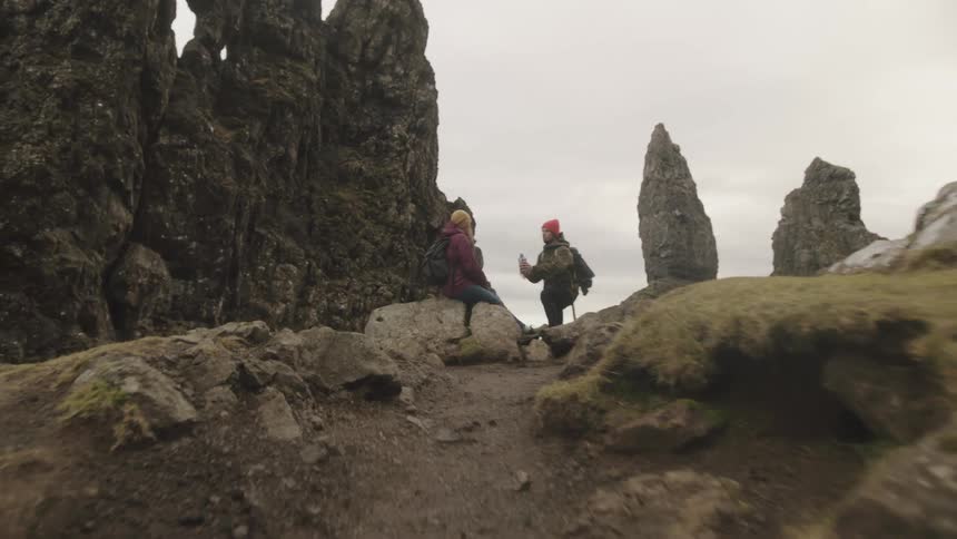 Shot up a dirt trail to a top of a hill with two hikers sharing a drink